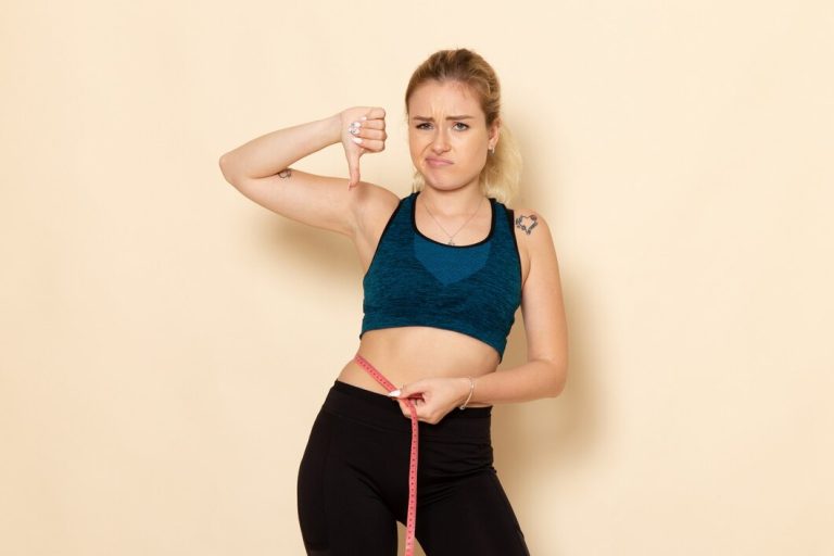 Breaking Down the Benefits of This Fat-Reducing Trend front view young female sport outfit measuring her body 140725 85460